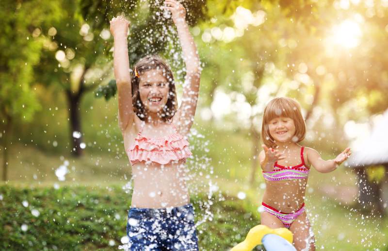 Mädchen spielen im Ferienlager mit Wasser