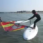 ein-teilnehmer-am-windsurfcamp-richtet-sein-segel-auf