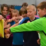 kinder-ueben-karate-mit-einem-brett-im-sportcamp