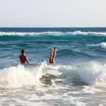 zwei-kinder-machen-kopfstand-im-meer-am-strand