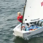 ein-junge-liegt-gut-im-wind-mit-einem-opti-segeln